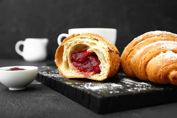 Board with tasty sweet croissants and jam on dark background — Stock Photo, Image