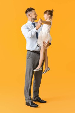 Babası ve küçük kızı renkli arka planda dans ediyorlar.