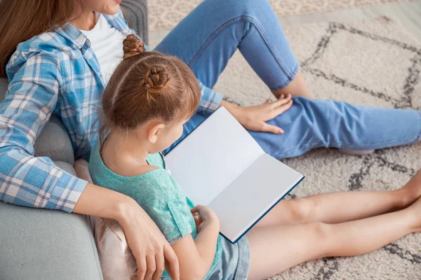 Piękna młoda kobieta i jej córeczka czytają książkę w domu — Zdjęcie stockowe