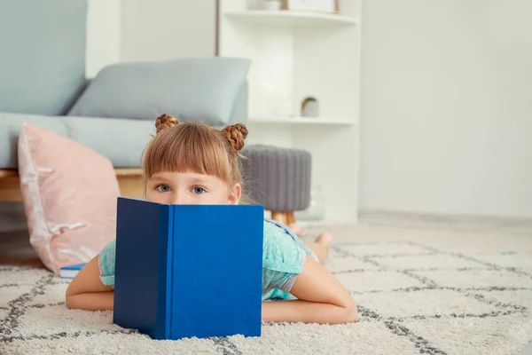 Cute little girl reading book at home — Stock Photo, Image