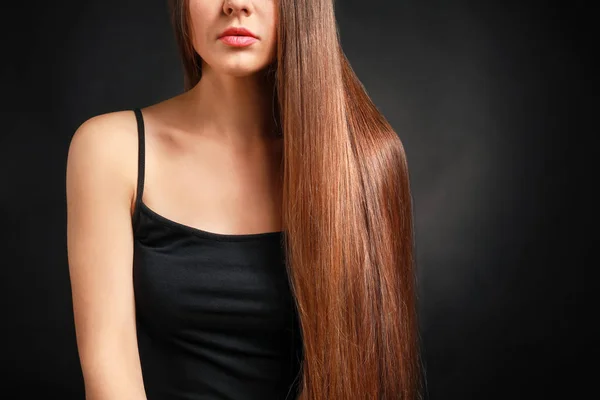 Mulher bonita com cabelos longos saudáveis no fundo escuro — Fotografia de Stock