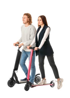 Young couple with kick scooters on white background