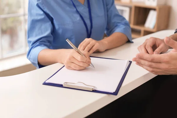 Young female receptionist working with patient in clinic, closeup — Stok fotoğraf