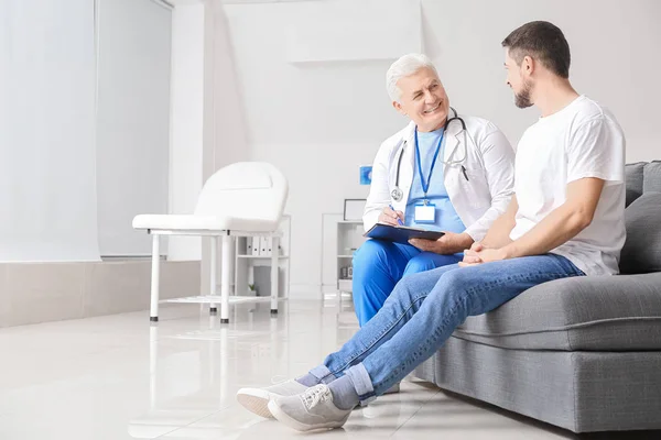 Volwassen mannelijke arts werkt met patiënt in kliniek — Stockfoto