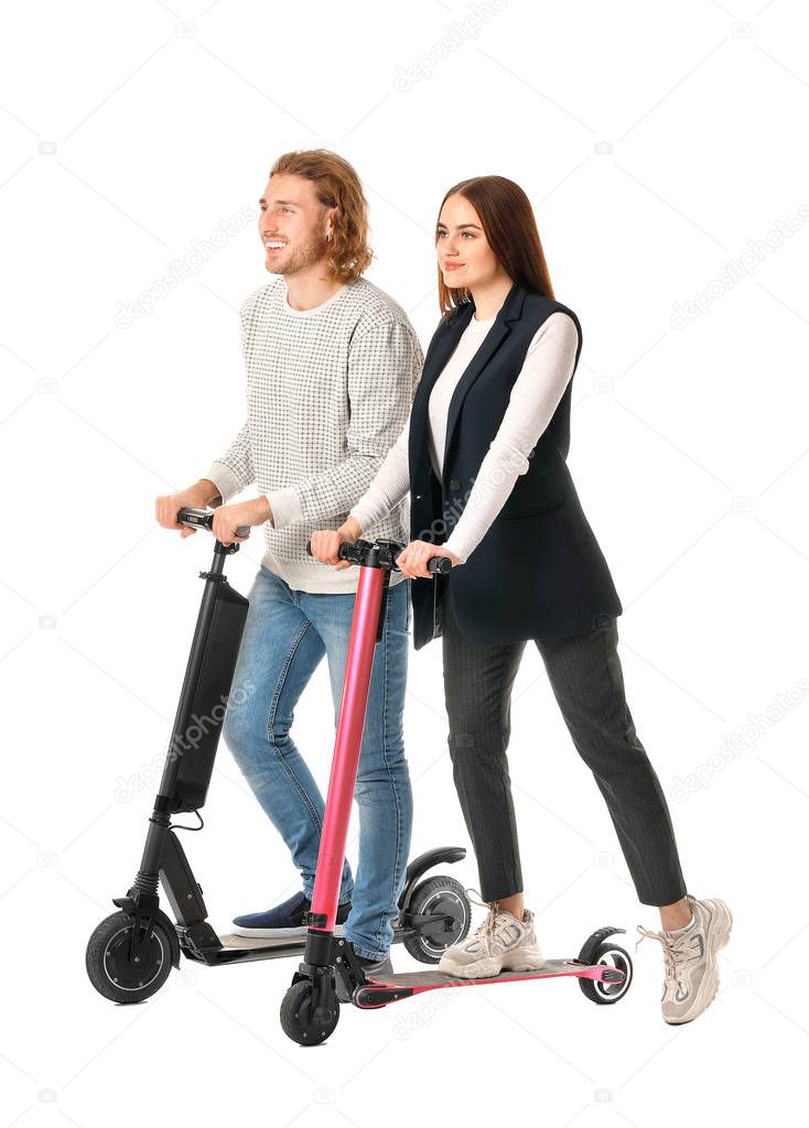 Young couple with kick scooters on white background