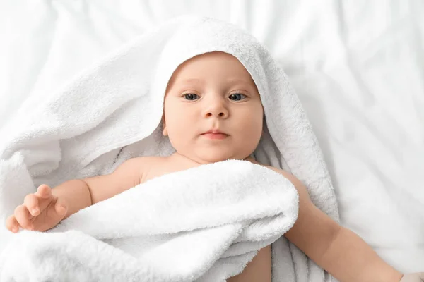 Портрет милого малыша с полотенцем, лежащим на кровати — стоковое фото