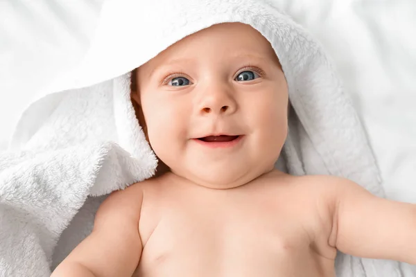 Portret van schattige baby met handdoek liggend op bed — Stockfoto