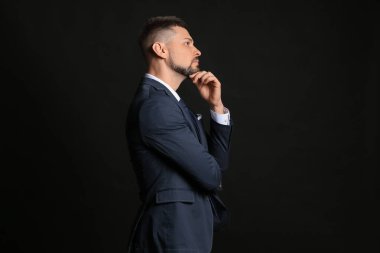 Thoughtful businessman on dark background. Concept of choice