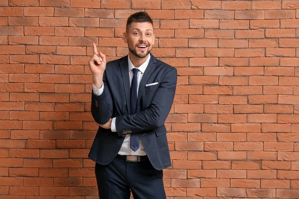 Businessman with raised index finger on brick background. Concept of choice — Stock Photo, Image