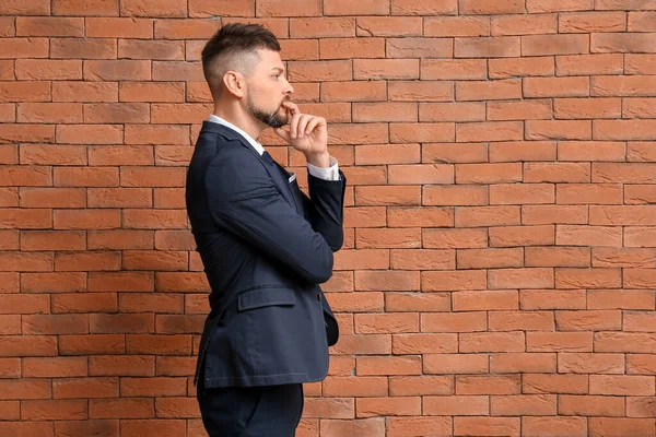 Pensativo hombre de negocios sobre fondo de ladrillo. Concepto de elección —  Fotos de Stock