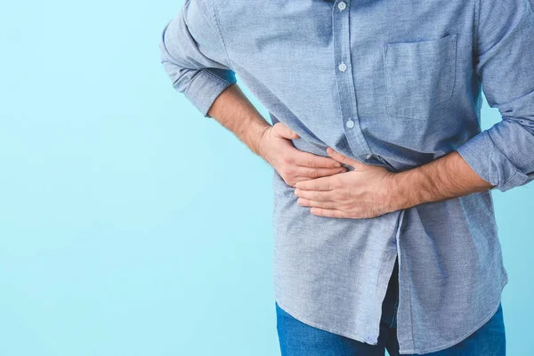 Young man suffering from abdominal pain on color background — Stock Photo, Image