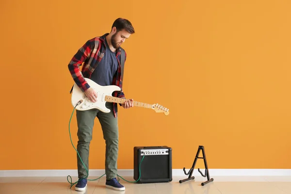 Young man playing guitar near color wall — Stock Photo, Image