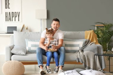 Father and his little daughter playing video games at home