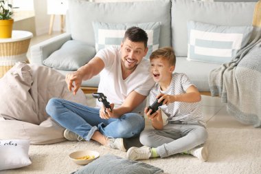 Babası ve küçük oğlu evde video oyunu oynuyorlar.