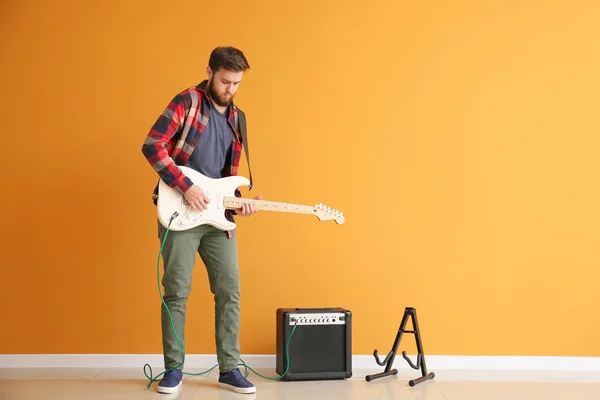 Young man playing guitar near color wall — Stock Photo, Image