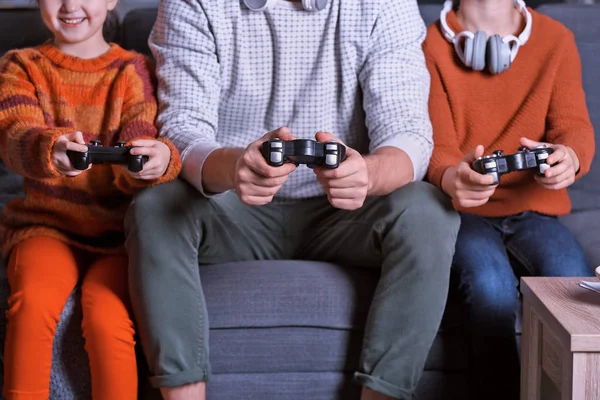Padre y sus hijos pequeños jugando videojuegos en casa por la noche —  Fotos de Stock