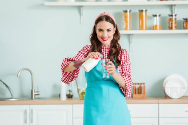 Beautiful housewife with milk in kitchen