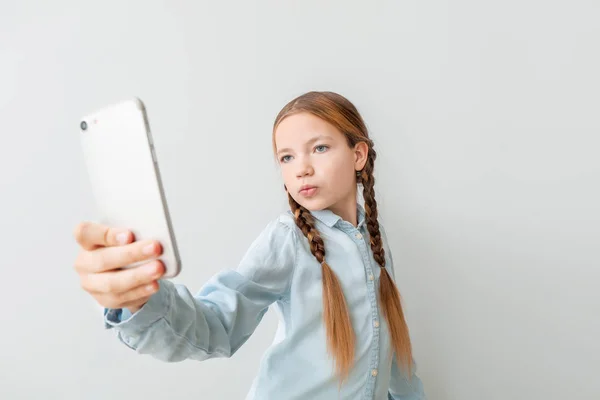 Söt liten flicka som tar selfie på ljus bakgrund — Stockfoto