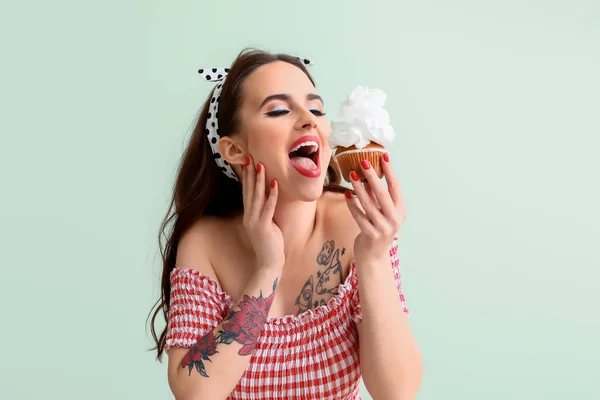 Beautiful housewife with cupcake on color background — Stock Photo, Image