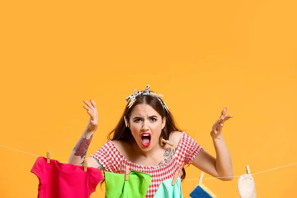 Angry housewife with laundry on color background — Stock Photo, Image