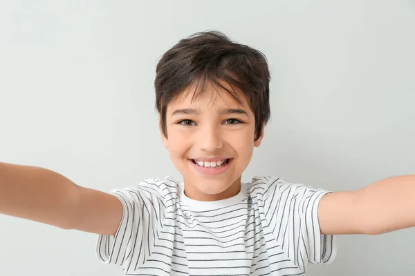 Carino piccolo ragazzo prendendo selfie su luce sfondo — Foto Stock