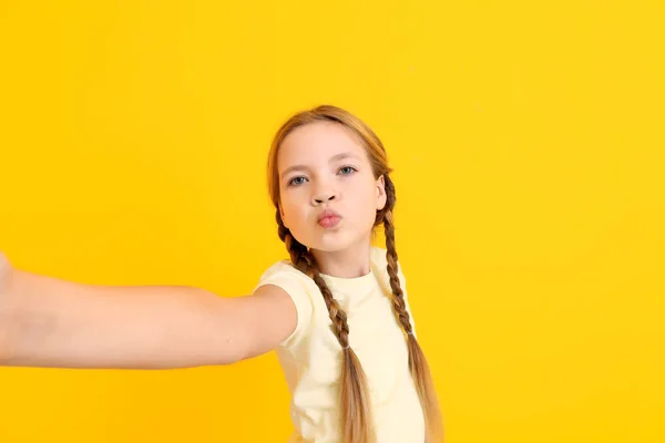 Carino bambina prendendo selfie su sfondo di colore — Foto Stock