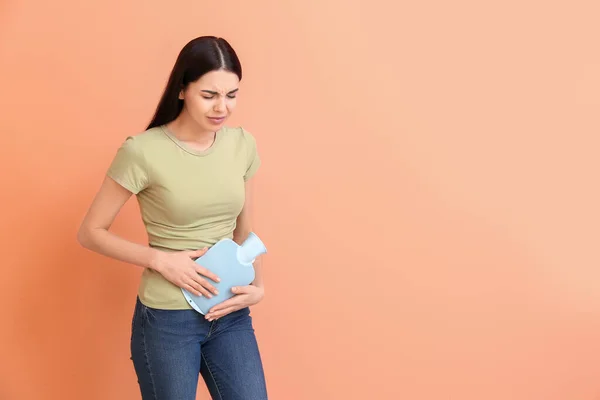 Young woman suffering from menstrual cramps on color background — Stock Photo, Image