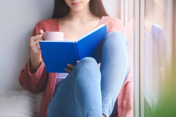 Молода жінка читає книгу вдома — стокове фото