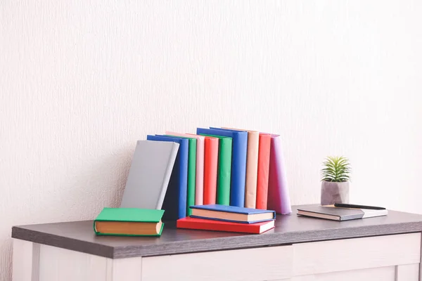 Veel boeken op tafel in de buurt van lichte muur — Stockfoto