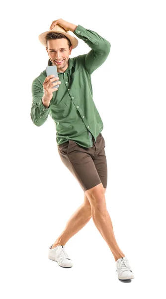 Cool young man with mobile phone dancing against white background — 图库照片