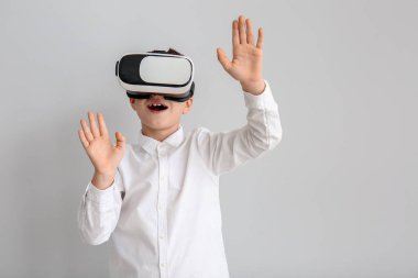 Gri arka planda sanal gerçeklik gözlüklü küçük çocuk.