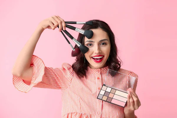 Bella giovane donna che applica il trucco su sfondo di colore — Foto Stock