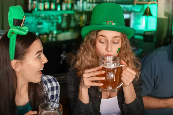 Jovens mulheres com cerveja comemorando o Dia de São Patrício no pub — Fotografia de Stock