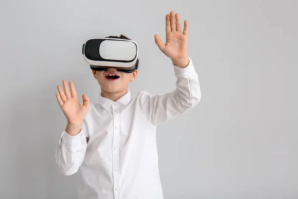 Kleiner Junge mit Virtual-Reality-Brille auf grauem Hintergrund — Stockfoto