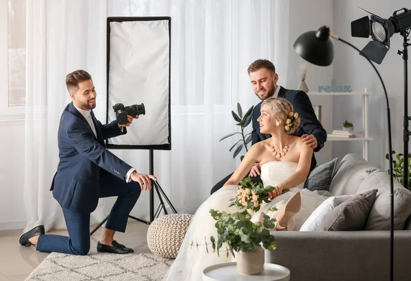 Photographer working with young wedding couple in studio — Stok fotoğraf