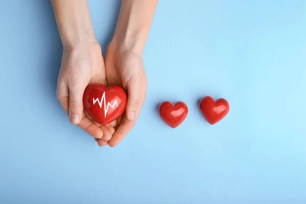 Female hands with red hearts on color background. Cardiology concept — Stock Photo, Image