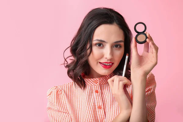 Beautiful young woman applying makeup on color background — Stock Photo, Image