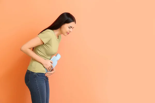 Young woman suffering from menstrual cramps on color background — 스톡 사진