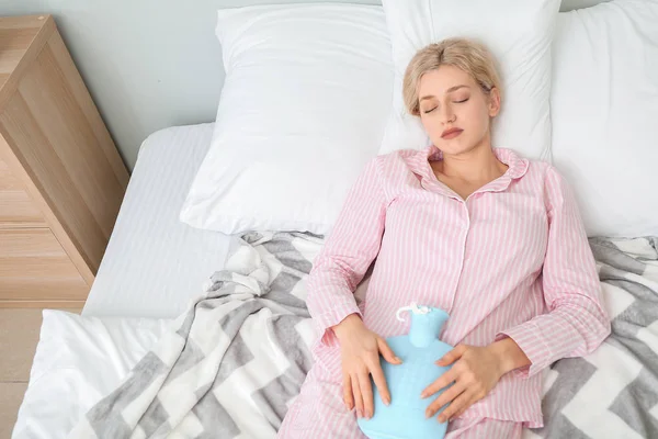 Mladá žena trpí menstruačními křečemi v ložnici — Stock fotografie
