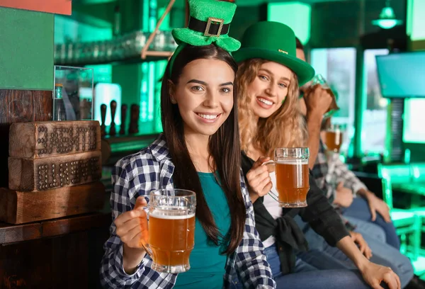 Young women with beer celebrating St. Patrick\'s Day in pub