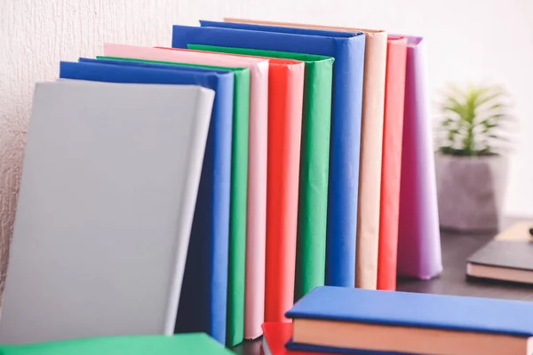 Many books on table near light wall — Stockfoto
