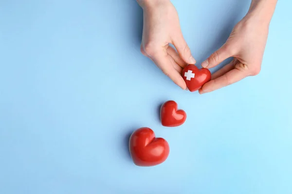 Weibliche Hände mit roten Herzen auf farbigem Hintergrund. Kardiologie-Konzept — Stockfoto