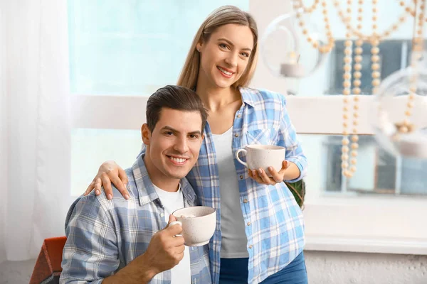 Feliz pareja bebiendo chocolate caliente en la víspera de Navidad en la cocina — Foto de Stock