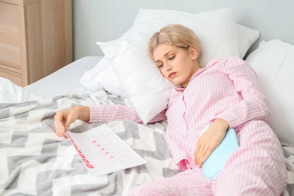 Young woman suffering from menstrual cramps in bedroom — 스톡 사진