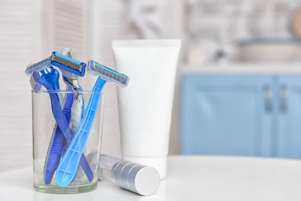 Razors for hair removal with cosmetics on table in bathroom — Stock Photo, Image