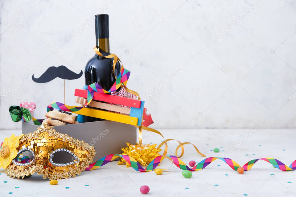 Box with tasty hamantaschen and party decor for Purim holiday on white background