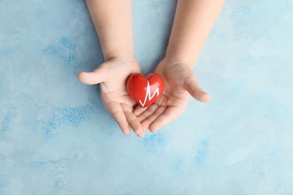 Child's hands with red heart on color background. Cardiology concept — Stock Photo, Image