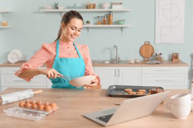 Young housewife cooking in kitchen