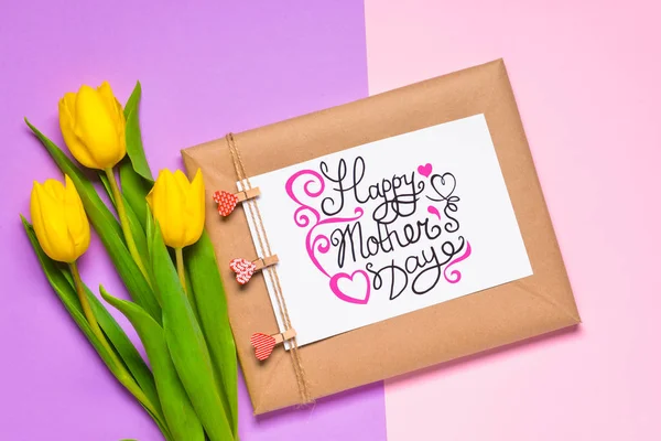 Beautiful flowers with greeting card and gift for Mother's Day on color background — Stockfoto