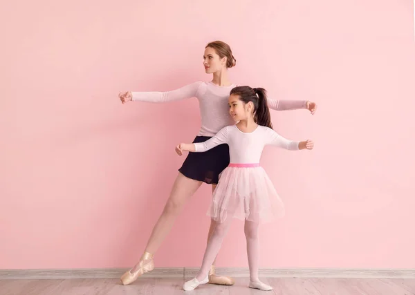Маленькая балерина тренируется с тренером на цветном фоне — стоковое фото